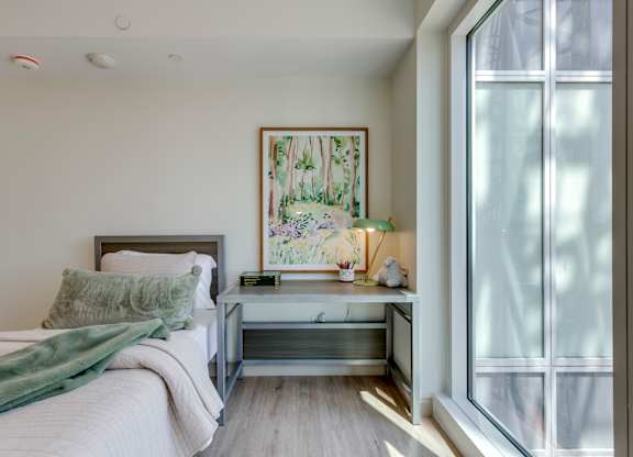 A bedroom with a bed, nightstand, and a painting on the wall.