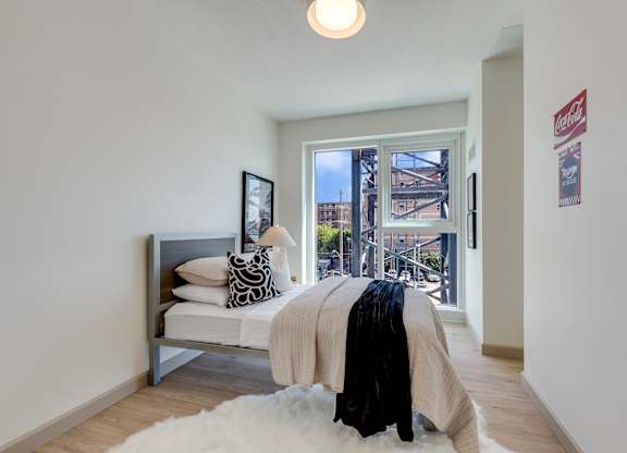 A bedroom with a bed and a window overlooking a city.