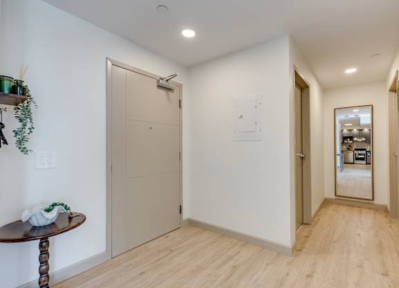 A hallway with a wooden floor and white walls.