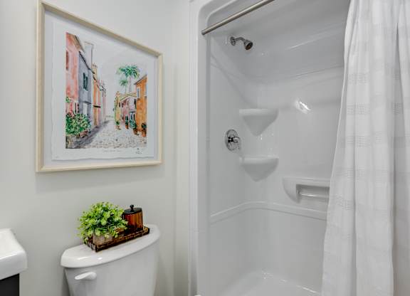 A white bathroom with a white toilet and a white bathtub.