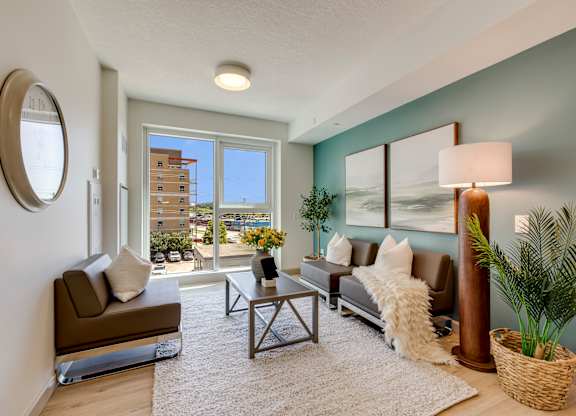 A living room with a brown couch, a coffee table, and a large window.