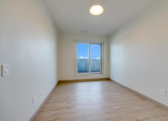 A room with a window and wooden flooring.