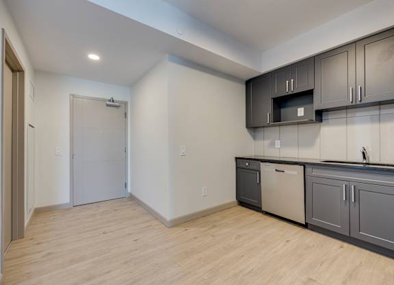 A kitchen with a white wall and a wooden floor.