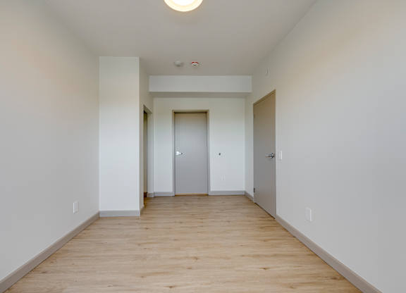 A long, empty hallway with a white door at the end.