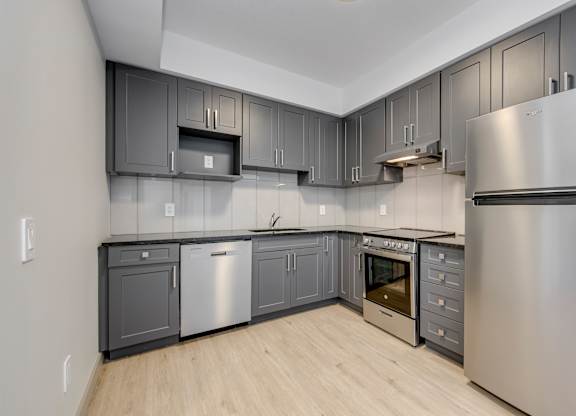 A modern kitchen with stainless steel appliances and wooden flooring.