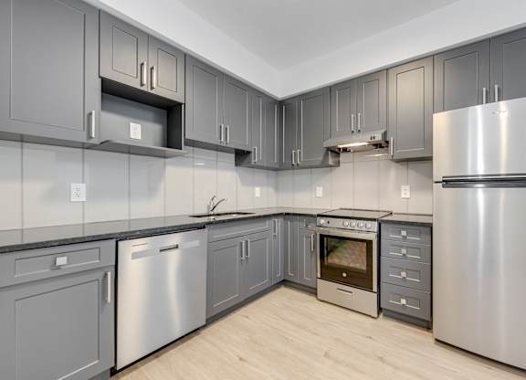 A modern kitchen with stainless steel appliances and grey cabinets.