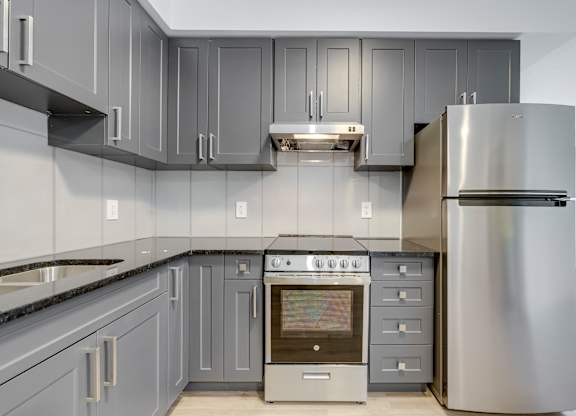 A modern kitchen with a stainless steel refrigerator and oven.