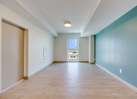 A long hallway with a door on the left and a window on the right.