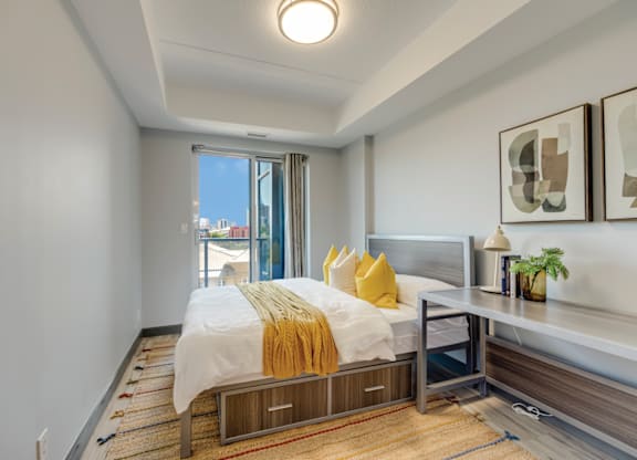 A bedroom with a bed, nightstand, and window.