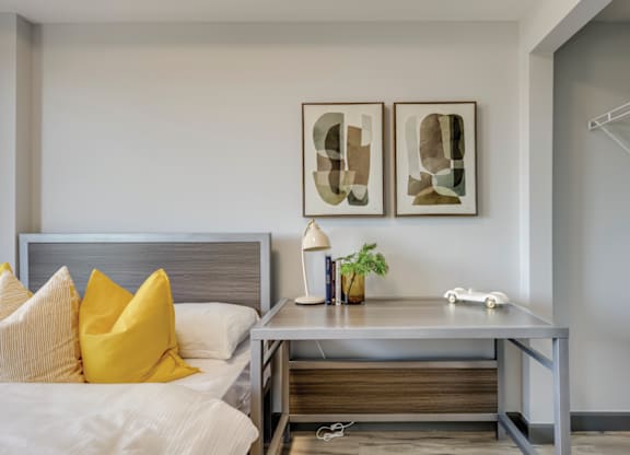 A bedroom with a bed, nightstand, and two framed artworks on the wall.