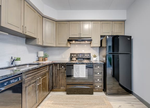 A kitchen with wooden cabinets and a black refrigerator.