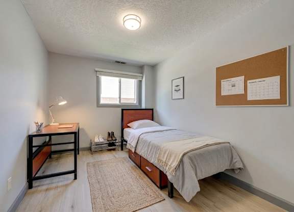 A bedroom with a bed, nightstand, and window.