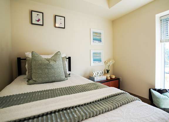A bed with a green and white striped blanket and a green pillow is in the foreground of the image.