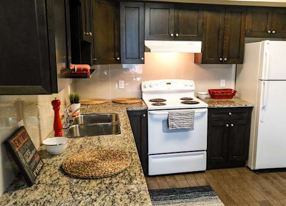 A kitchen with a white stove and black cabinets.