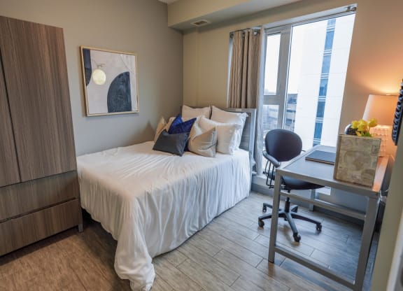 a bedroom with a bed and a desk and a window