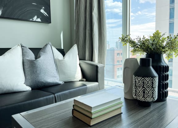 a living room with a couch and a table with books and a vase