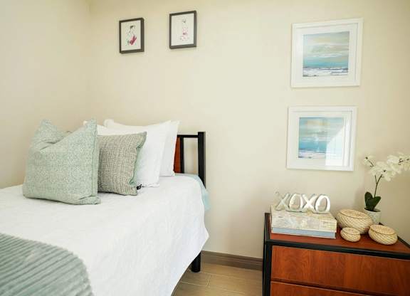 A bedroom with a bed, nightstand, and pictures on the wall.
