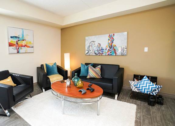 A living room with a black couch, a coffee table, and two chairs.
