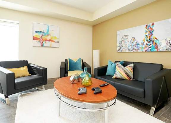 A living room with a black couch, a black chair, and a coffee table.