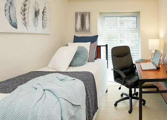 A bedroom with a bed, chair, and two framed pictures on the wall.
