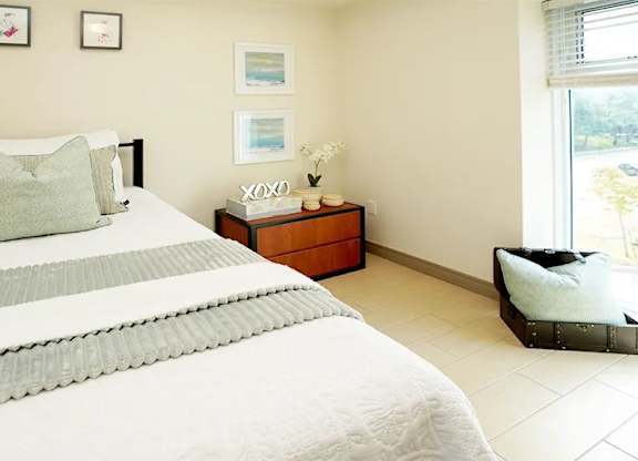 A bedroom with a large bed and a nightstand with a vase of flowers on it.