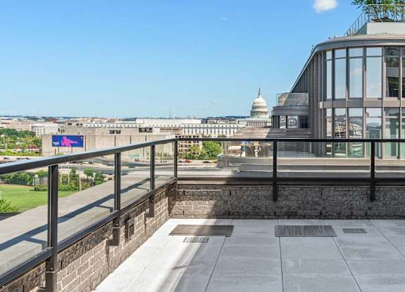 A penthouse balcony with a view of the U.S. Capitol and a building with a glass facade.