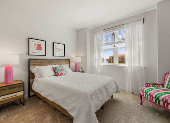 A bedroom with a bed, a chair, and two pictures on the wall.