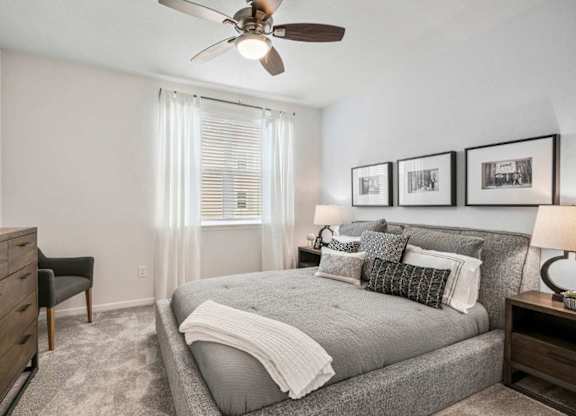 A bedroom with a bed, dresser, and ceiling fan.