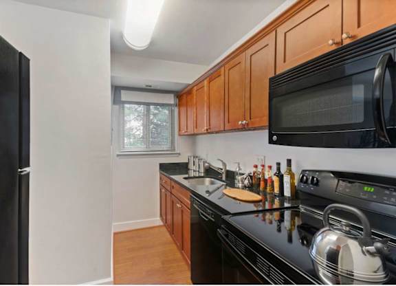 A kitchen with black appliances and wooden cabinets.