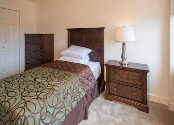 A bedroom with a bed, nightstand, and lamp.