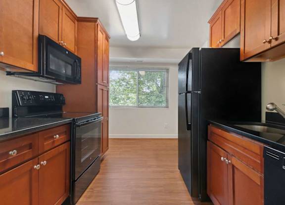 A kitchen with black appliances and wooden cabinets.