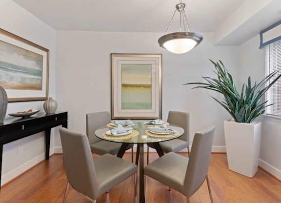A dining room with a table set for two and a potted plant.