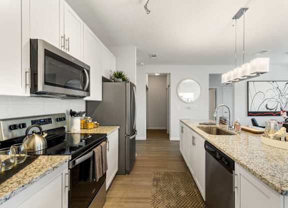 A modern kitchen with granite countertops and stainless steel appliances.
