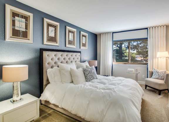 A bedroom with a large bed and a window overlooking a tree.