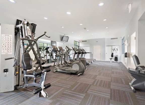 A gym with a variety of equipment including treadmills, weights, and exercise machines.