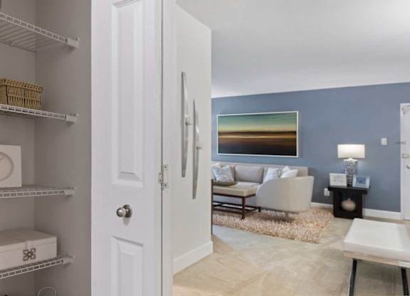 A white door is open to a living room with a couch and a painting on the wall.