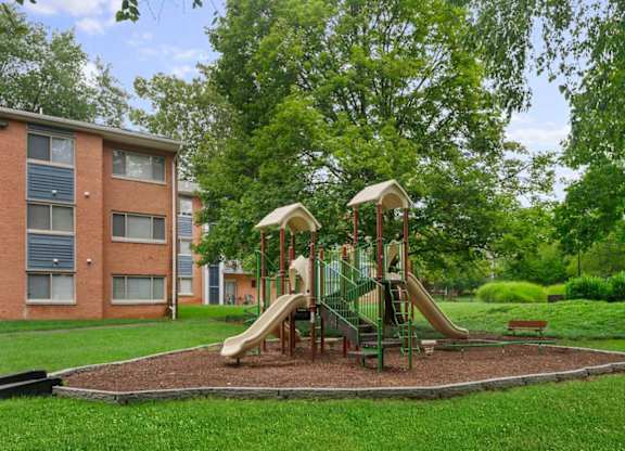 A playground with a slide and swings in a grassy area.