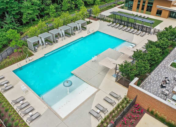 An outdoor swimming pool surrounded by lounge chairs and trees.