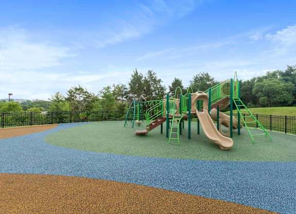 A playground with a slide and plenty of fenced in space.