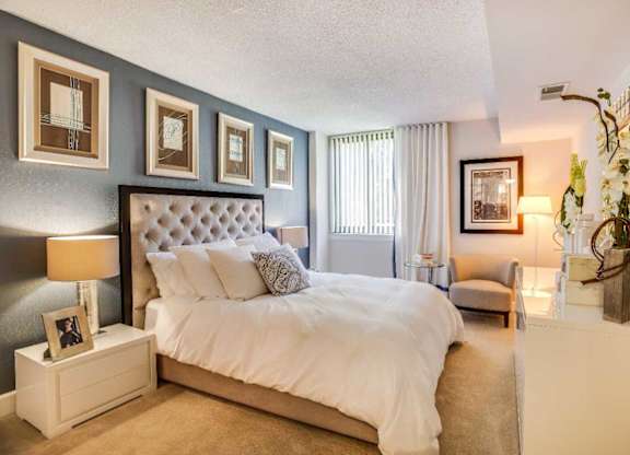 A bedroom with a large bed and a nightstand with a lamp.