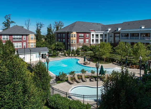 A large swimming pool surrounded by trees and buildings.