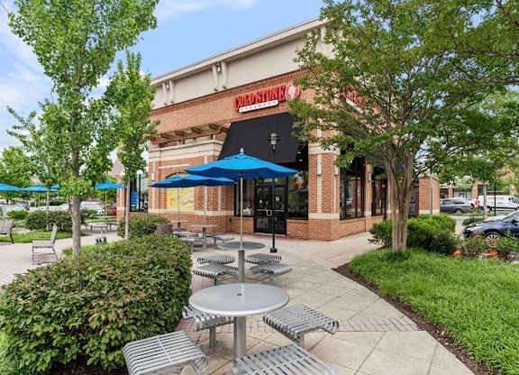 a patio outside of a restaurant with tables and umbrellas