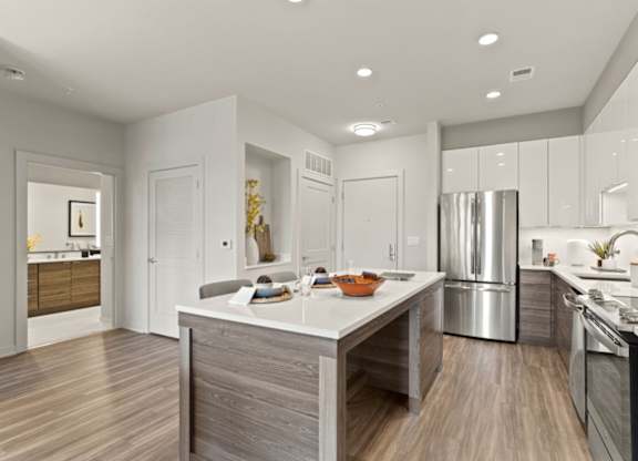 a kitchen with a large island and a stainless steel refrigerator