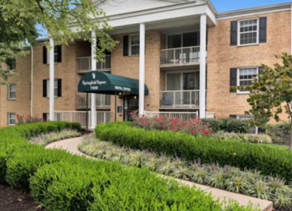 a brick building with a green awning and a garden in front of it