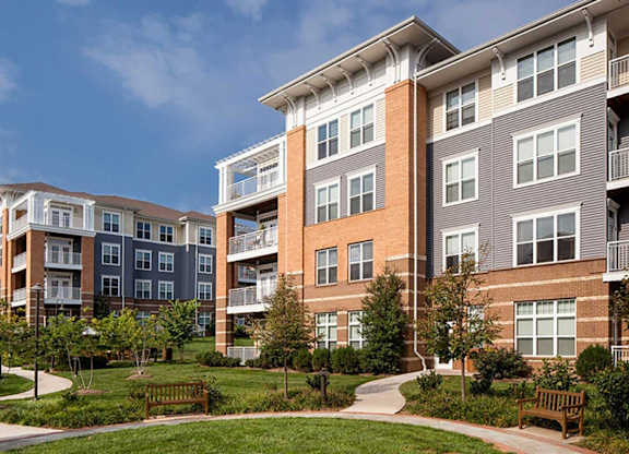 an exterior view of an apartment complex with benches and grass