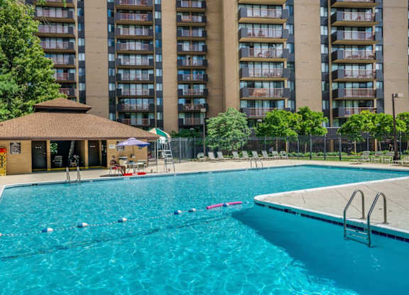 A swimming pool with a diving board and a building in the background.