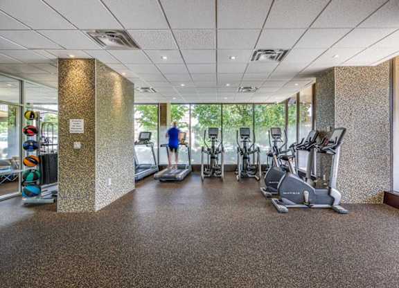 A gym with a variety of exercise equipment including treadmills, stationary bikes, and elliptical machines.