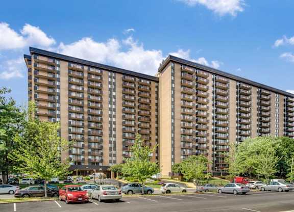 A large apartment building with a parking lot in front.