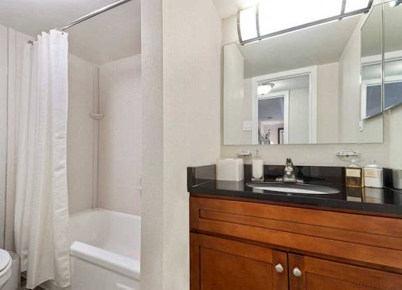 A bathroom with a toilet, a bathtub, a sink and a mirror.