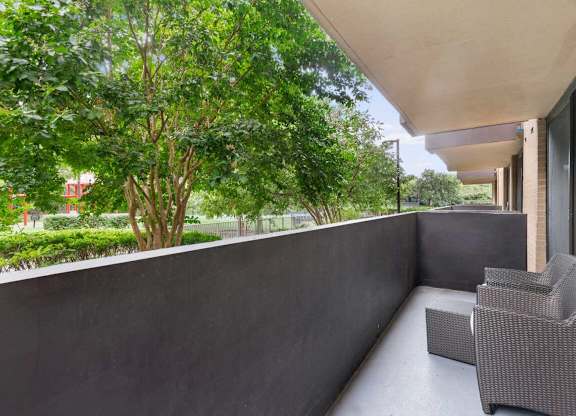 A balcony with a grey chair and a concrete wall.